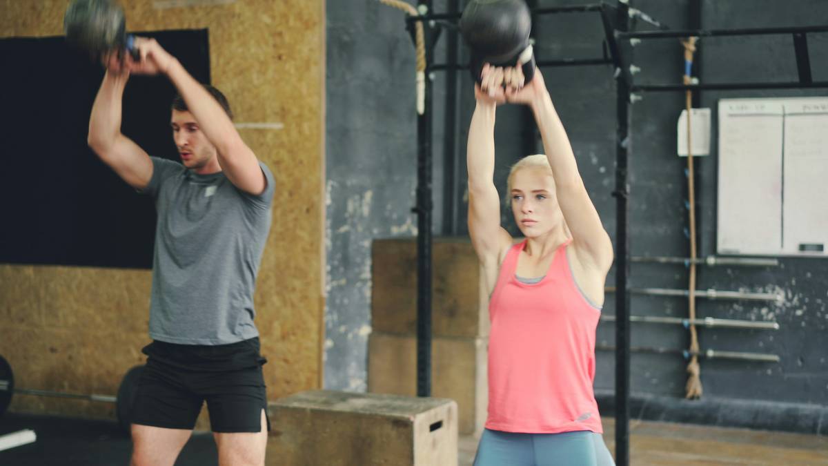 Woman performing iron burn workout routine with kettlebells in home gym